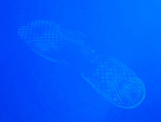White footprint from a boot smeared with whitewash on a blue background close-up.