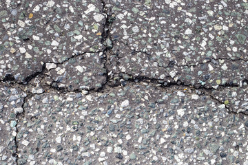 gray asphalt with a crack, interspersed with fine gravel. Road surface texture