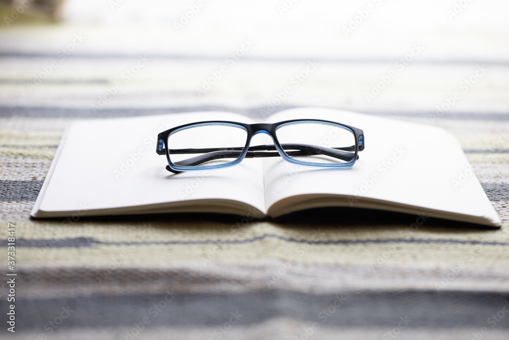 Poster closeup shot of an opened notebook with eyeglasses on it