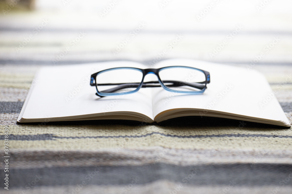 Poster closeup shot of an opened notebook with eyeglasses on it