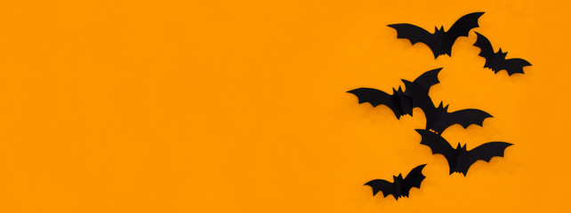 Halloween and decoration concept - black paper bats flying over orange background