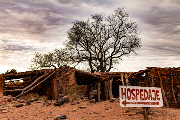 Desert landscape of Argentina. Red earth and dry grasslands. "Lodging" sign in the foreground.