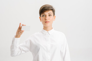  girl in a white office shirt holds out a business card. close portrait.