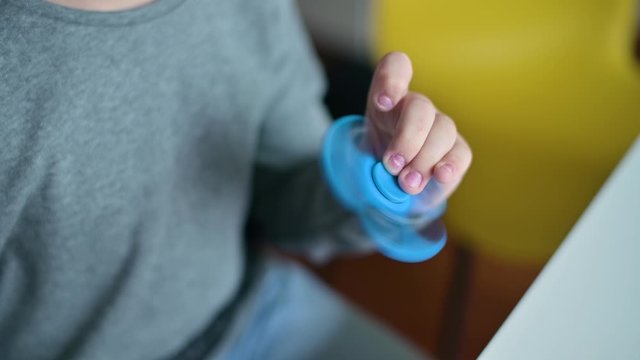 a toy spinner is spinning in the hands of a boy. The guy is messing around. No face, close up