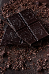 Broken dark chocolate bar on brown background. Closeup view