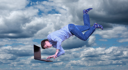 young man with laptop flies in the sky