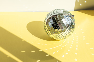 Shining disco ball on yellow background. Disco ball with bright rays