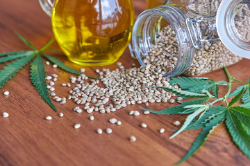 Fototapeta premium seeds hemp on the table, oil in a glass jar, cannabis leaves isolated on white background
