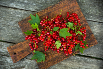 Ripe red currant berries on a cutting board on an old wooden background. Harvesting.