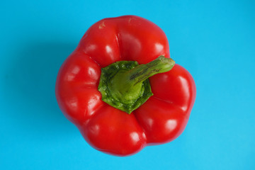close up a large juicy red pepper on a blue background top view