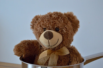 Brown teddy bear smiling in a silver pot. © Designak