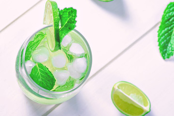 High glass of a drink with lime, ice cubes and mint for the summer