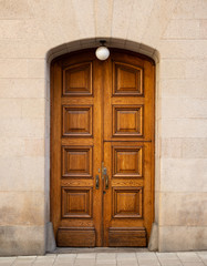 Old wooden double door in stone building with lamp above
