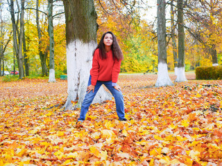 young girl on a background of fallen yellow foliage in the park