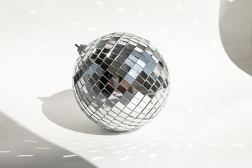 Shining disco ball on white background with hard shadows. Disco ball with bright rays