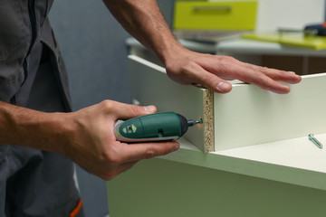 furniture assembly service worker assembles a kitchen cabinet with drawers. 