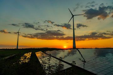 wind turbines and modern solar panels in the rural landscape at sunset