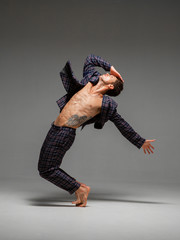 Handsome young guy dancer in suit and barefoot dancing expressive dance. Dance school poster. Body with tattoo