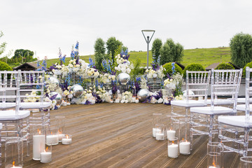 Wedding reception with white, blu and violet flower and candles, outdoors. Elegant luxury wedding decoration composition on ceremony place