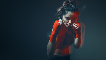 Beautiful female fighter trains in boxing bandages in studio on gray background. Women's mixed martial arts poster