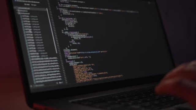 Software computer programming code, typing in laptop. Close up of screen with programming code, working programmer typing on black screen