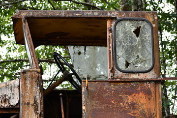 Cabin to large logging machine abandoned in woods.