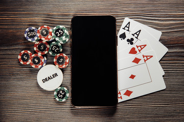 Poker chips and smartphone on a wooden background. Poker online concept.