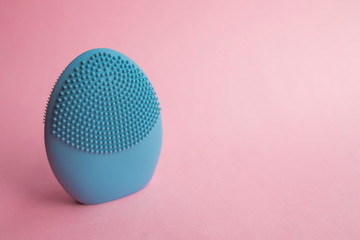 Blue facial cleansing brush on pink background. Beauty and skincare concept. Brush for face...
