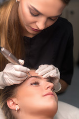 Fototapeta premium Permanent eyebrow makeup. Cosmetologist applying tattooing of eyebrows.