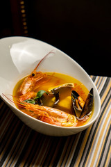 Bouillabaisse fish soup with prawns, mussels, tomato ,lobster and squid. Traditional in France, Spain. Black rustic background. Flat lay.
