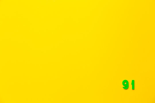 A green plastic toy number ninety-one is located in the lower right corner on a yellow background
