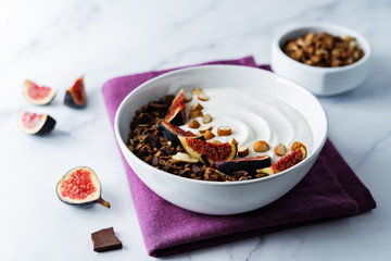 Greek yogurt chocolate almond nuts oatmeal granola with figs in a bowl