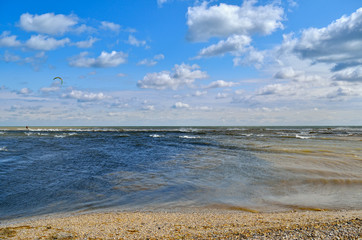 Sea waves wash the beach against a blue sky. Landscape on a wild beach. The sea in the summer.