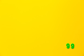 A green plastic toy number ninety-nine is located in the lower right corner on a yellow background