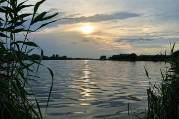 Fototapeta na wymiar Sunbeams at sunset are reflected in the lake