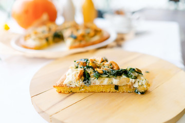 Slice of pumpkin pie with chanterelles. A carved pumpkin in the background. Traditional Halloween dish served on a table with a white tablecloth on a wooden cutting board.