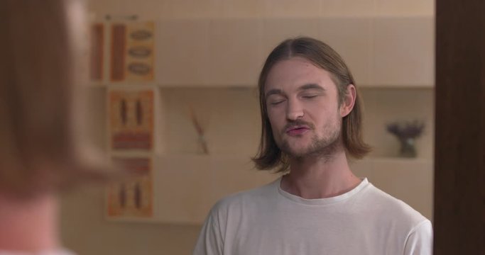 Young man looks at himself in the mirror with satisfaction and gesture &ldquo;yes&rdquo;