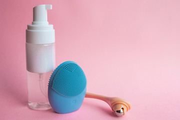 Silicone brush for washing face and cosmetic foam. Beauty and skincare concept.  Blue facial...