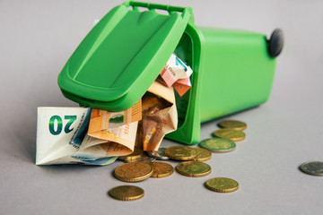 trash can with euro banknotes and coins, medical mask, syringe, thermometer - crisis concept	