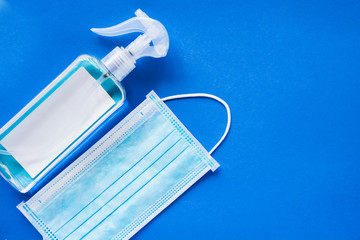 disposable hygienic face mask and Bottle of hand sanitizer, antimicrobial liquid spray, germ prevention or antibacterial hygiene on blue background