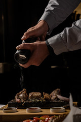 sirloin steak on a very hot stone being cooked by a man to his own taste on a wooden table with a knife and fork