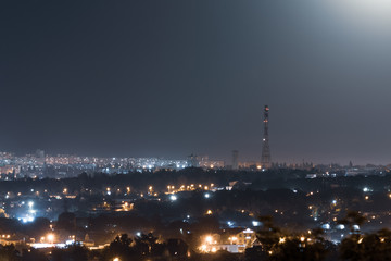 Night time city lights blue colors dark sky panorama. Big city lightened with bright moon light. Colorful romantic clear sky night view