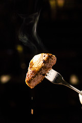 sirloin steak on a very hot stone being cooked by a man to his own taste on a wooden table with a knife and fork