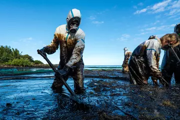 Fotobehang Schipbreuk Vrijwilligers reinigen de oceaankust van olie na een tankerwrak. Mauritius