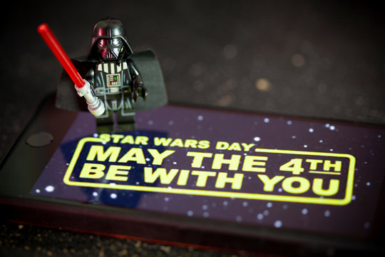 NEW YORK USA, APRIL 28 2019:  Darth Vader Lego Mini Figure with Star Wars wallpaper on an iPhone screen for Star Wars Day concept May the 4th Be With You