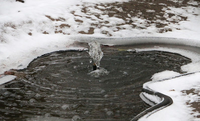 Closeup shot of a water fountain in a frozen snowy park