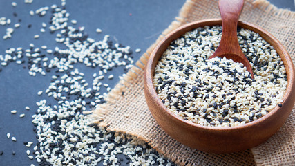Organic natural sesame seeds wooden spoon. toasted sesame seeds. Raw, whole, unprocessed. Natural light. Selective focus. Close up on a black background. Top view, flat lay. copy space for text.
