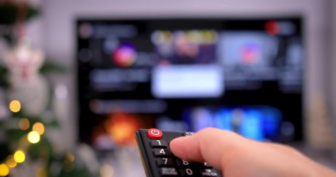 Accessing apps on smart TV with remote control. Searching among different apps on smart television. Using device and smart technology on Christmas time. 4k