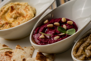 Colorful hummus bowls, healthy vegan dips. Traditional Middle eastern hummus, green hummus, beetroot hummus, spread. Assorted meze and dips with pita bread. Meze and snacks set, copy space.
