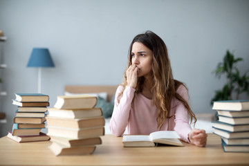 Tired student girl at the table with a lot of books. Homework school or university.